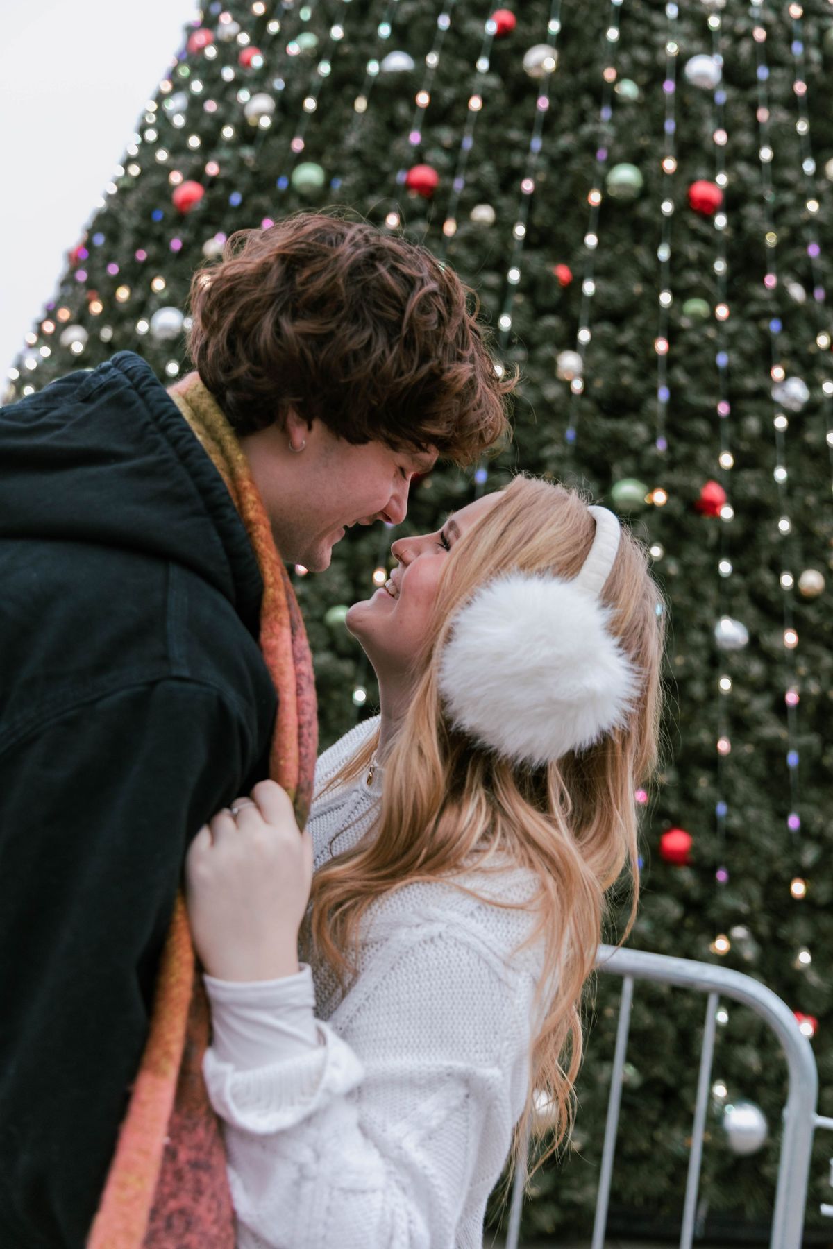 A couple at the Christmas tree, ear muffs and laughter