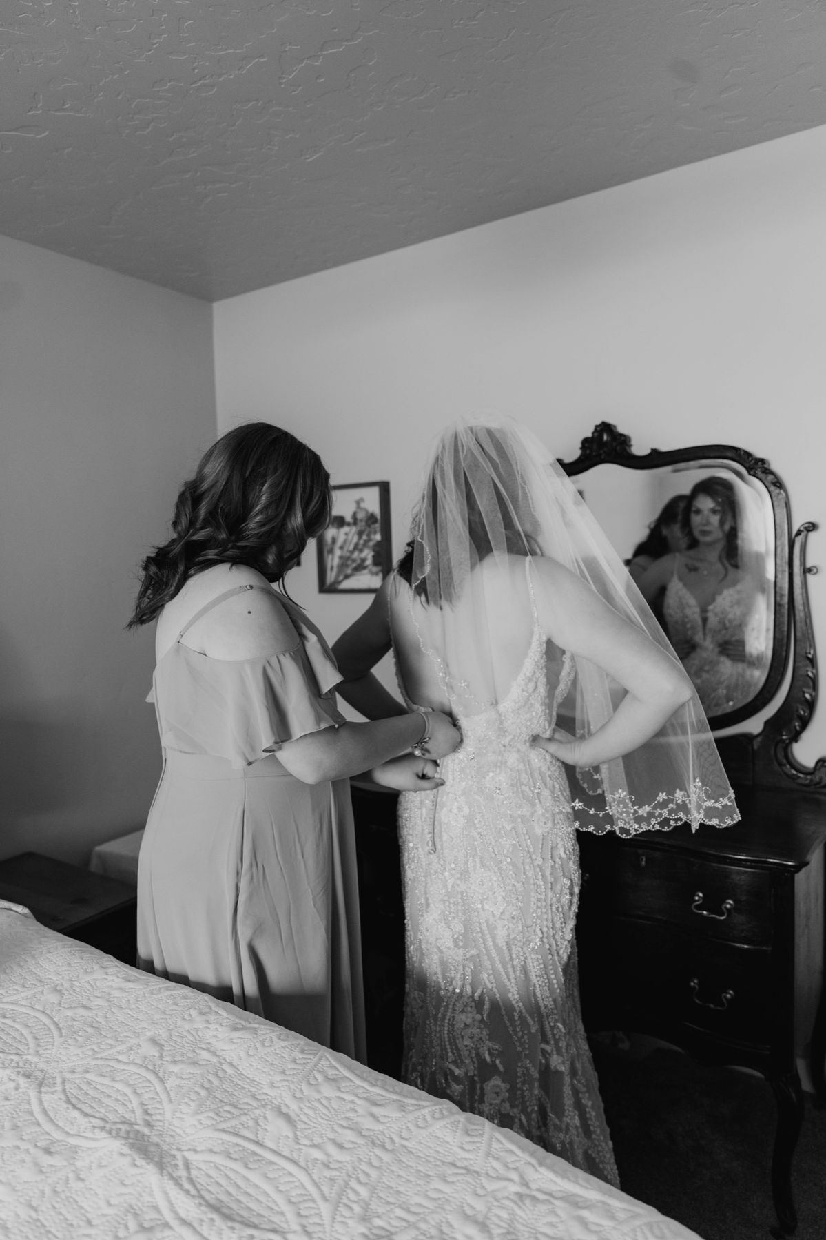 A bride getting ready at the mirror with her mother, black and white